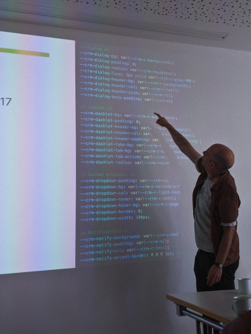 Bald guy pointing at CSS variables on a projection.