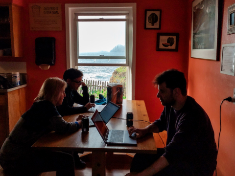 Three sprint participants working hard on their laptops in the CiviKitchen in front of scenic ocean window